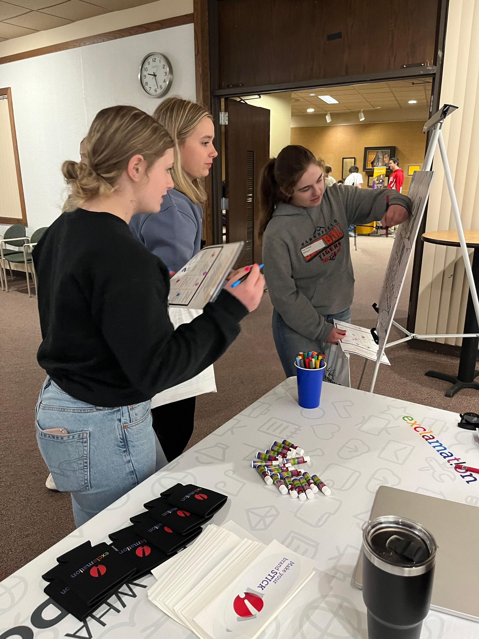 3 students coloring on a board Exclamation created at a career expo