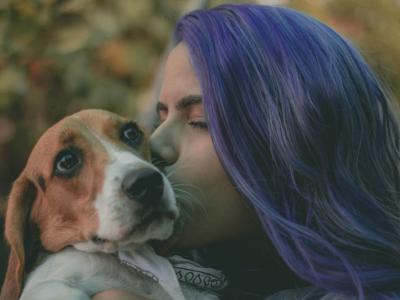 A person with purple hair holding a basset hound