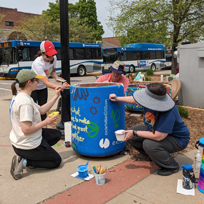 exterior of street corner with people painting a garbage can