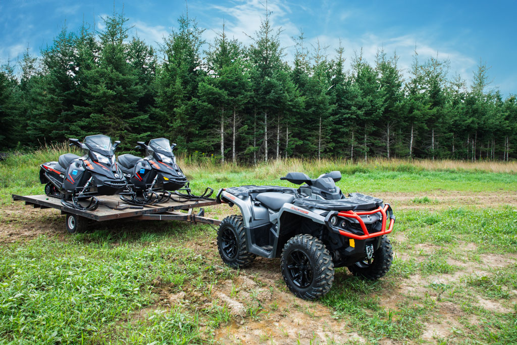 ATV pulling 2 snowmobiles on trailer