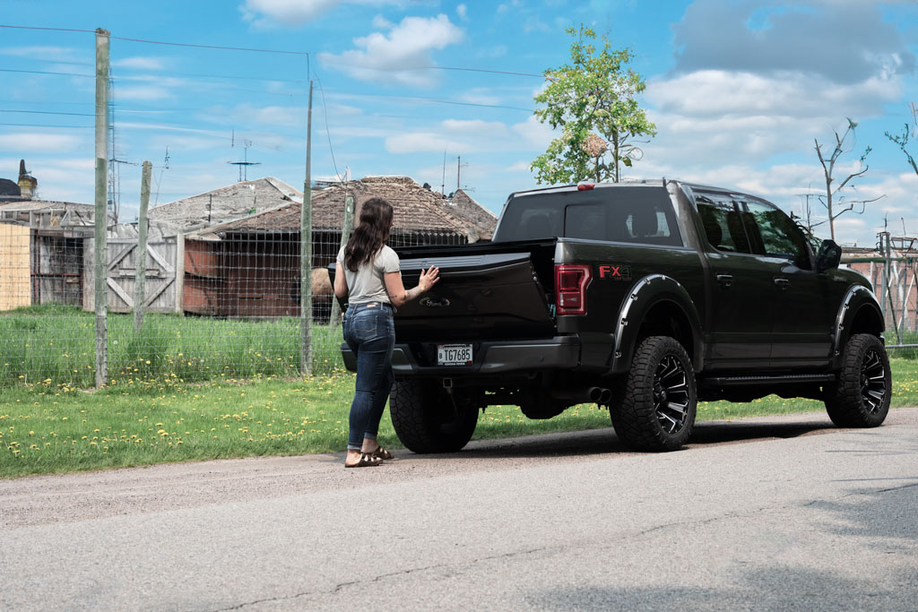 Woman closing tailgate of black truck