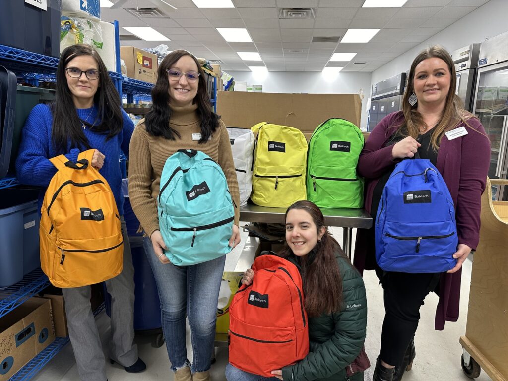 Simplcity CU staff with colorful backpacks they filled for the unhoused population. 